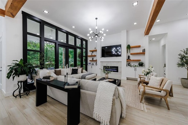 living room with light wood finished floors, beamed ceiling, a notable chandelier, and a premium fireplace