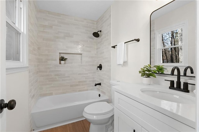 bathroom featuring wood finished floors, toilet, vanity, and  shower combination