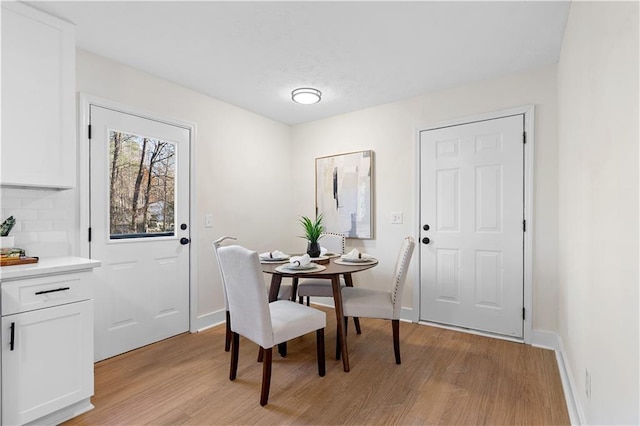 dining area featuring baseboards and light wood-type flooring