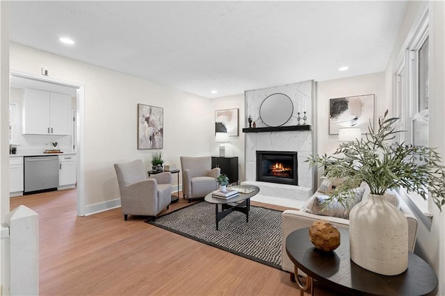 living room featuring baseboards, recessed lighting, light wood-style flooring, and a fireplace