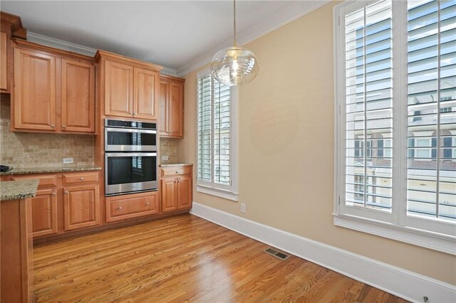 kitchen with light stone counters, tasteful backsplash, stainless steel double oven, light hardwood / wood-style flooring, and ornamental molding