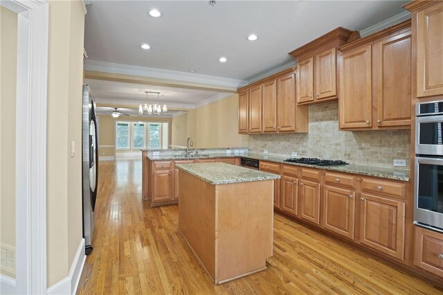 kitchen with kitchen peninsula, a kitchen island, light hardwood / wood-style flooring, decorative light fixtures, and ornamental molding