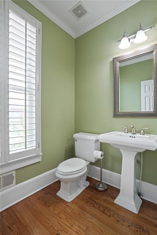 bathroom featuring wood-type flooring, crown molding, toilet, and a healthy amount of sunlight