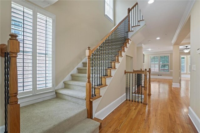 staircase featuring wood-type flooring and ornamental molding