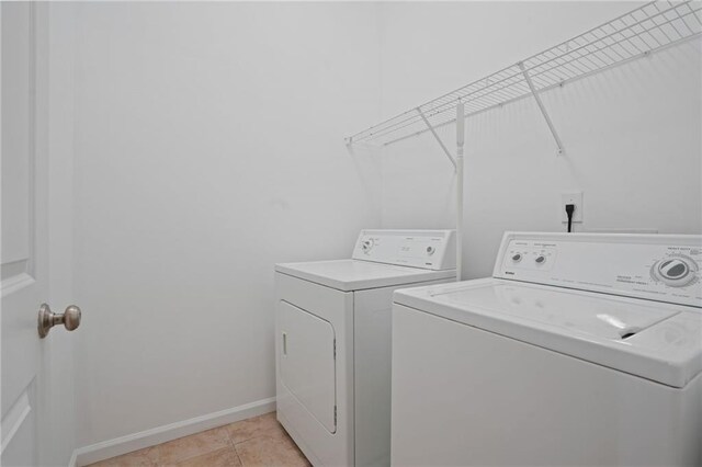 clothes washing area with separate washer and dryer and light tile patterned floors