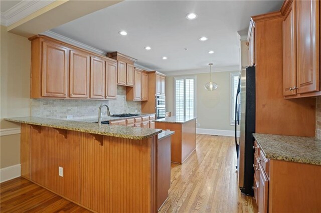 kitchen with light stone counters, tasteful backsplash, kitchen peninsula, light wood-type flooring, and crown molding