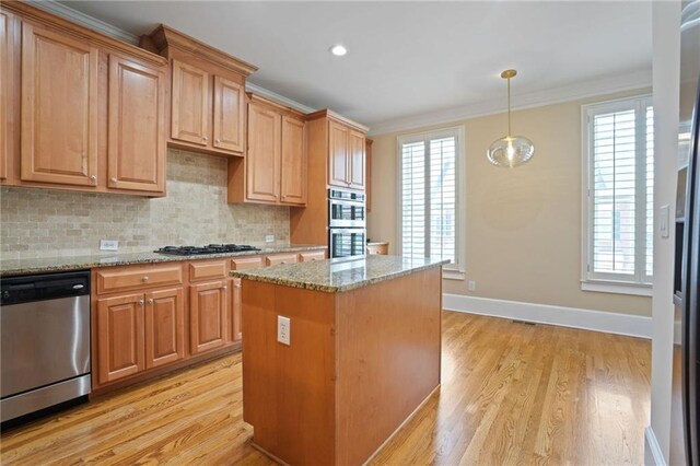 kitchen with appliances with stainless steel finishes, a kitchen island, light stone countertops, and plenty of natural light