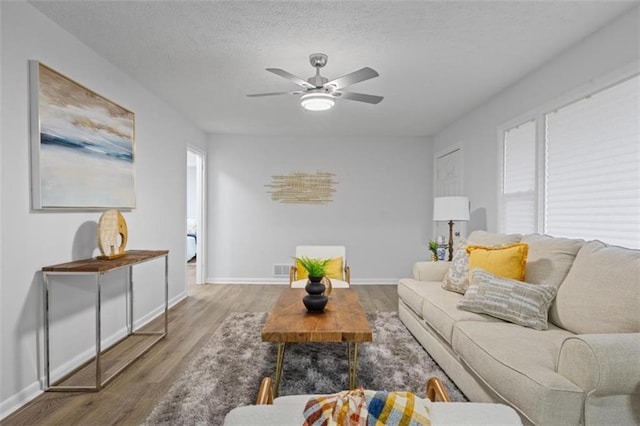 living room featuring ceiling fan, wood-type flooring, and a textured ceiling