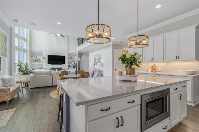 1865 Henley Way, Alpharetta, GA 30009 - kitchen with stainless steel microwave, a kitchen island, decorative backsplash, open floor plan, and ornamental molding