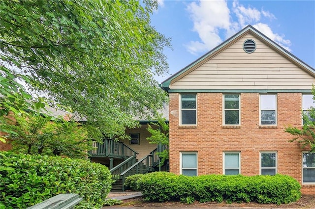 view of front of property featuring stairs, brick siding, and a deck