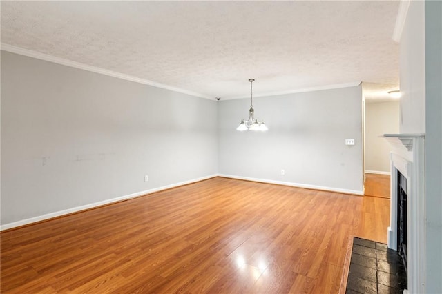 unfurnished living room with a textured ceiling, a chandelier, a fireplace with flush hearth, light wood finished floors, and crown molding