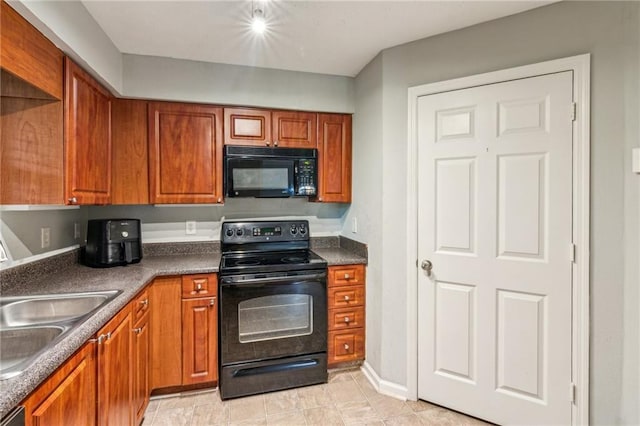 kitchen featuring black appliances, a sink, dark countertops, and brown cabinetry