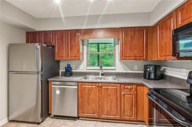 kitchen with black appliances, a sink, brown cabinets, and dark countertops