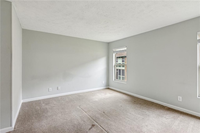 spare room featuring carpet floors, baseboards, and a textured ceiling