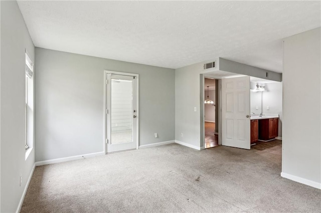 carpeted spare room with baseboards, a textured ceiling, and a sink
