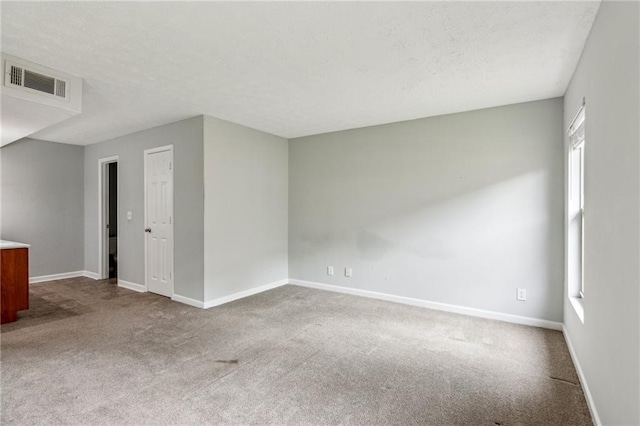 spare room with carpet flooring, healthy amount of natural light, baseboards, and a textured ceiling