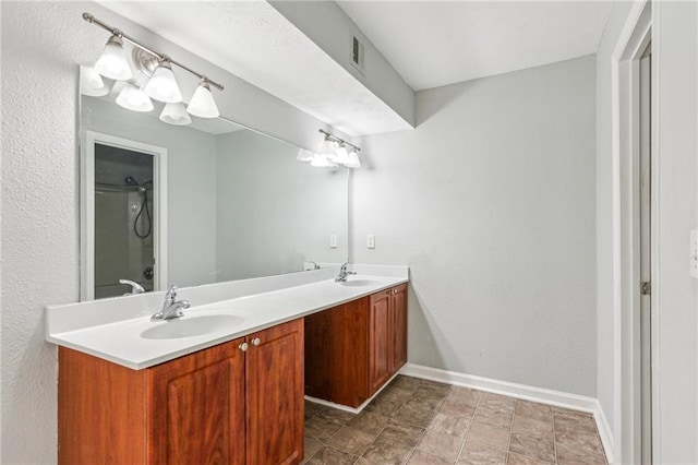 bathroom with double vanity, baseboards, and a shower