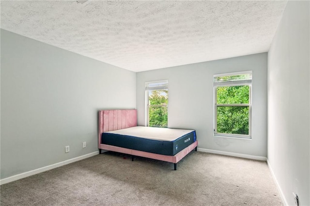 carpeted bedroom featuring a textured ceiling and baseboards