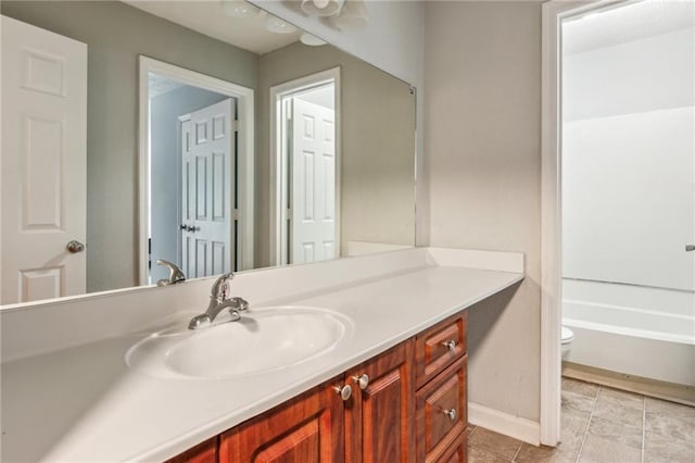 full bathroom with vanity, baseboards, toilet, a bathtub, and tile patterned floors