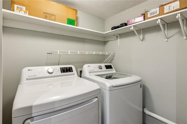 washroom with washing machine and clothes dryer and a textured ceiling