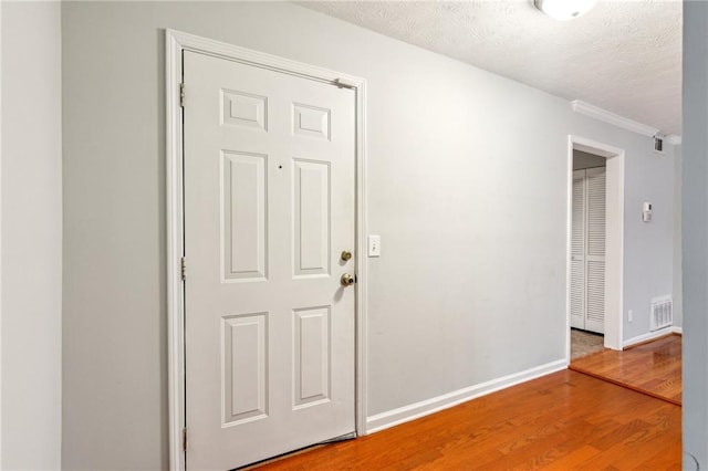 spare room featuring wood finished floors, a textured ceiling, baseboards, and ornamental molding
