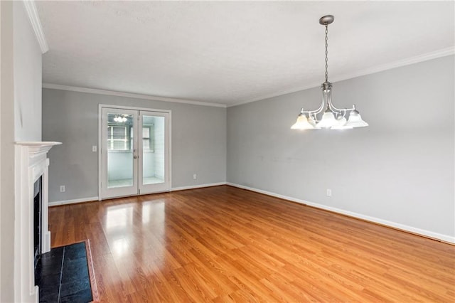 unfurnished living room featuring a chandelier, wood finished floors, baseboards, ornamental molding, and a fireplace