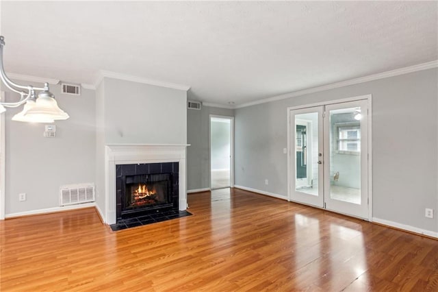unfurnished living room with wood finished floors, healthy amount of natural light, baseboards, crown molding, and a fireplace