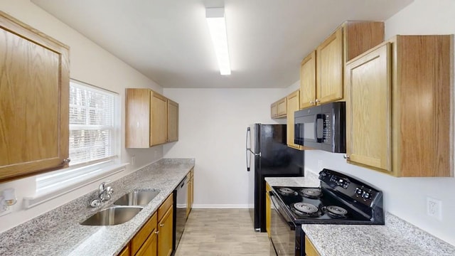 kitchen featuring light brown cabinetry, light stone countertops, black appliances, and a sink