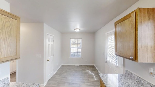 unfurnished dining area featuring light wood-type flooring and baseboards