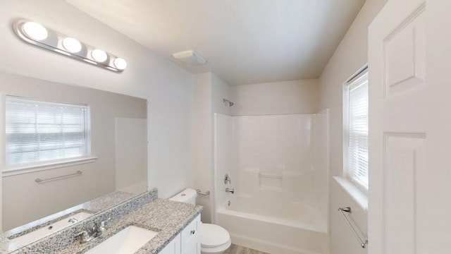 full bathroom featuring washtub / shower combination, plenty of natural light, toilet, and vanity