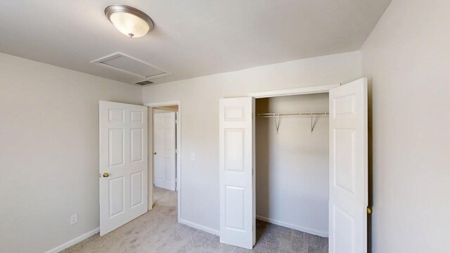 unfurnished bedroom with baseboards, visible vents, light carpet, and attic access