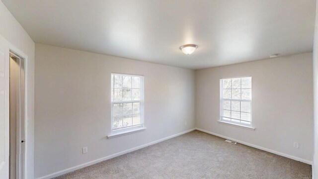 spare room with visible vents, baseboards, and carpet flooring