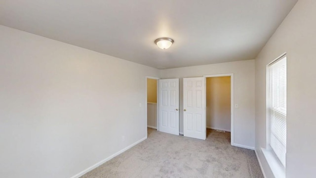 unfurnished bedroom featuring light colored carpet and baseboards