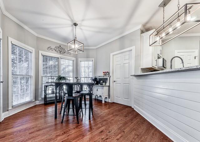 dining space with a premium fireplace, a ceiling fan, crown molding, and wood finished floors