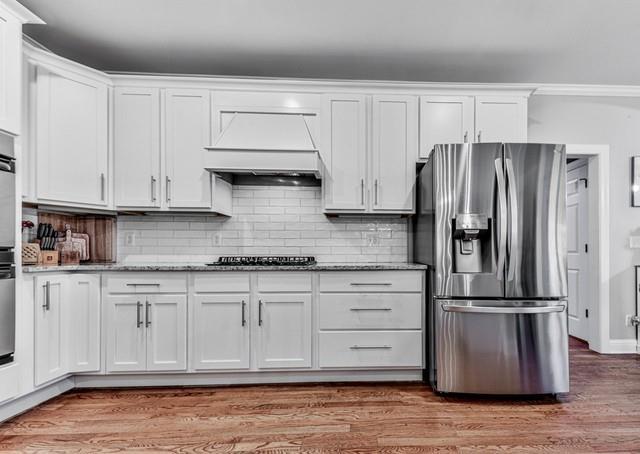 kitchen featuring a breakfast bar, a peninsula, white cabinetry, appliances with stainless steel finishes, and wood finished floors