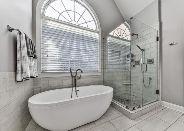 full bathroom featuring a freestanding bath, double vanity, a sink, and tile walls