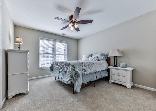 bedroom with visible vents, light colored carpet, baseboards, and a ceiling fan