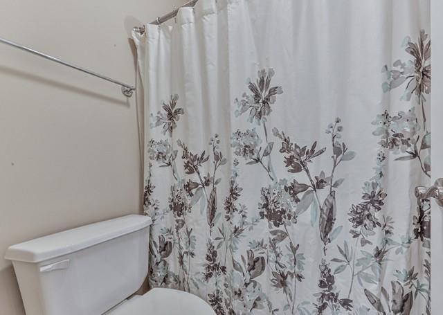 bedroom with visible vents, baseboards, a ceiling fan, connected bathroom, and light carpet