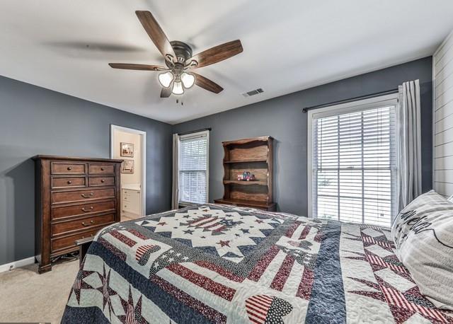 bedroom with light carpet, visible vents, and baseboards