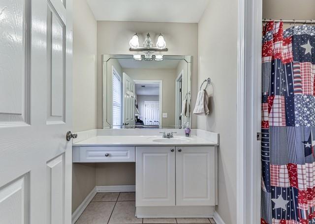 full bath featuring tile patterned floors, toilet, curtained shower, and baseboards