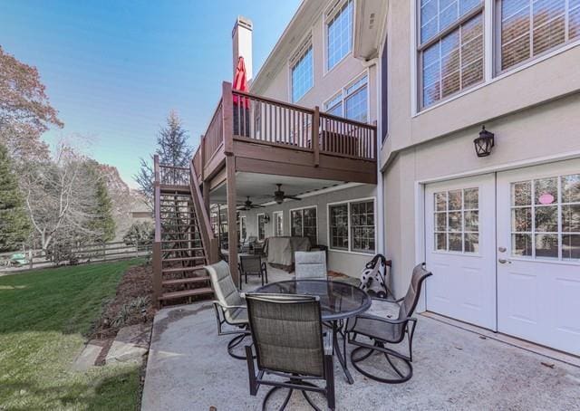view of patio with outdoor dining space, ceiling fan, and stairs