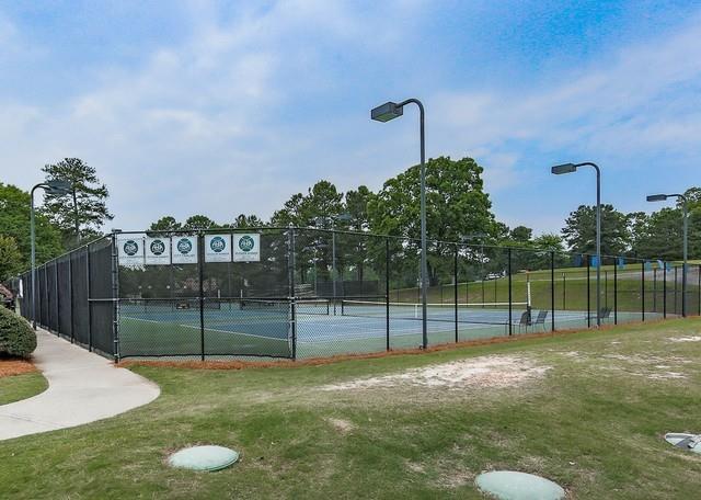 view of tennis court featuring a yard and fence