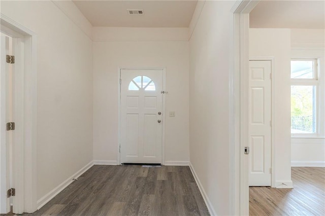 foyer entrance featuring visible vents, baseboards, and wood finished floors