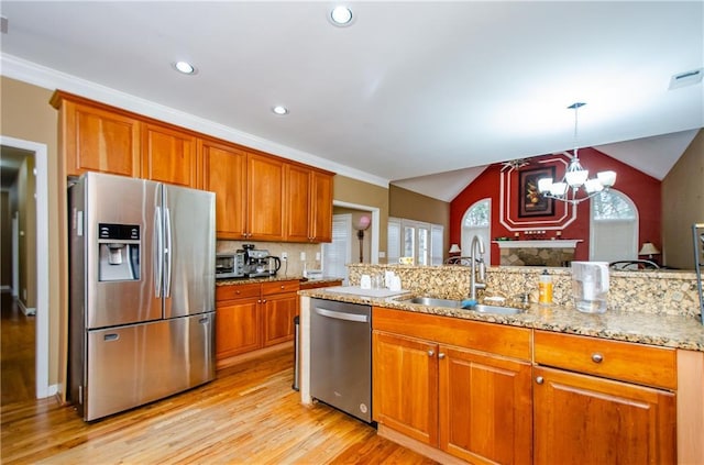 kitchen with sink, stainless steel appliances, light stone counters, tasteful backsplash, and decorative light fixtures