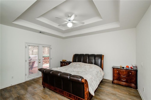 bedroom with dark hardwood / wood-style flooring, access to exterior, ceiling fan, a tray ceiling, and french doors