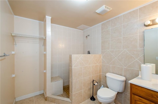 bathroom featuring vanity, toilet, tile walls, and tiled shower