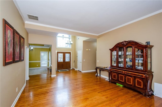 entryway with wood-type flooring and crown molding