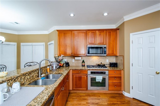 kitchen with sink, crown molding, stainless steel appliances, and light hardwood / wood-style floors