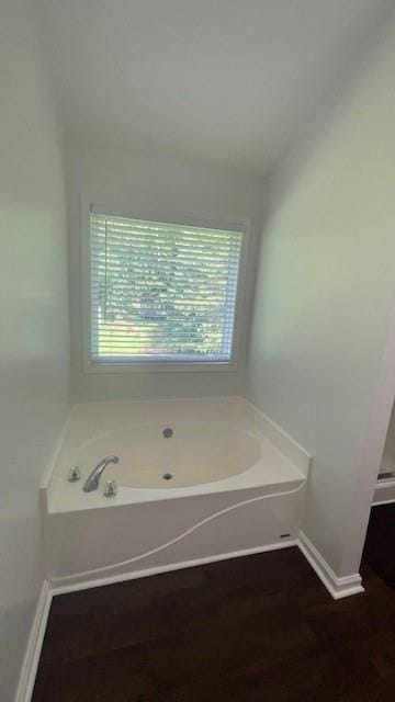 bathroom with wood-type flooring and a tub to relax in