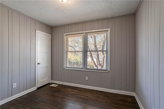spare room with dark wood-type flooring, plenty of natural light, and a textured ceiling